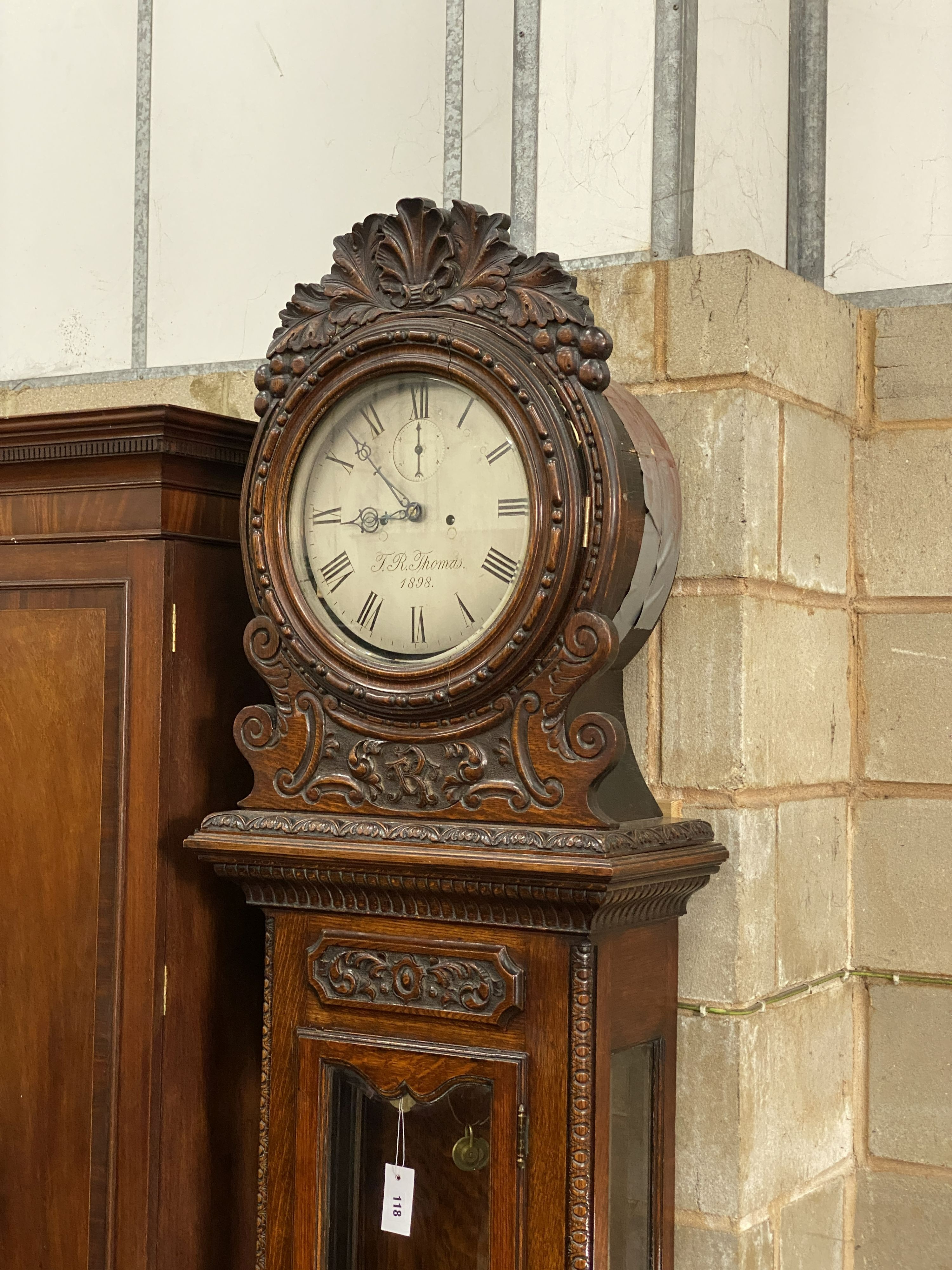 A Victorian carved oak eight day longcase clock by J.R.Thomas dated 1898, having silvered circular dial over glazed door, height 226cm